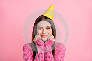 Photo of pretty dreamy young woman dressed knitted sweater birthday headwear smiling arms cheeks isolated pink color