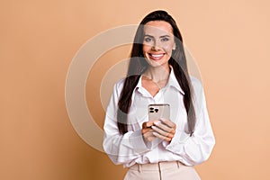 Photo of pretty elegant girl toothy smile hold smart phone empty space ad isolated on beige color background