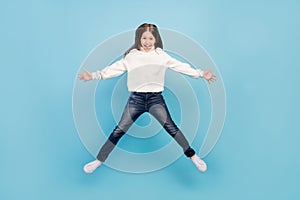 Photo of pretty excited student girl wear white sweater smiling jumping high like star isolated blue color background
