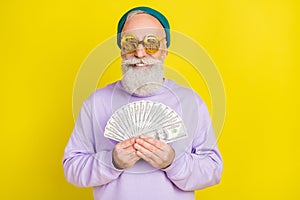 Photo of pretty funky mature man dressed purple pullover eyewear smiling holding money fan isolated yellow color