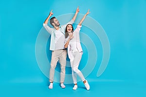 Photo of pretty funky young couple wear casual shirt pointing empty space dancing isolated blue color background