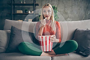 Photo of pretty funny lady homey mood eating popcorn watching television horror show eyes full of fear sitting comfort