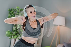 Photo of pretty funny young girl dressed sport suit headphones practicing dancing aerobics smiling indoors house home