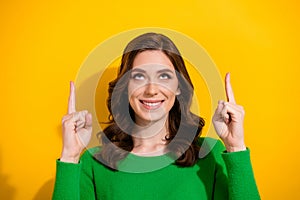 Photo of pretty girl toothy smile look direct fingers up empty space offer isolated on yellow color background