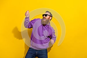 Photo of pretty handsome guy dressed purple sweater dark eyewear dancing isolated yellow color background