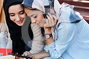 Photo of pretty islamic girls wearing headscarfs sitting in green park