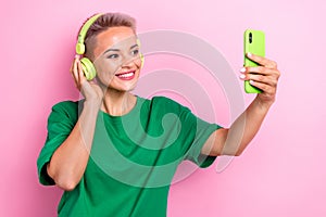 Photo of pretty lady hand touch headphones hold smart phone make selfie isolated on pink color background