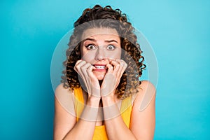 Photo of pretty nervous student girl gnaw nails scared look camera wear yellow tank-top isolated blue color background