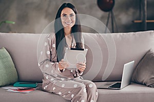 Photo of pretty optimistic girl sit write tablet wear spectacles pijama at home on sofa photo