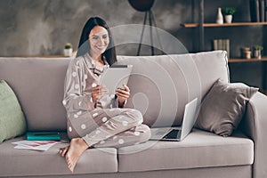 Photo of pretty optimistic girl sit write tablet wear spectacles pijama at home on sofa photo