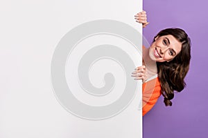 Photo of pretty positive young funny woman hiding behind huge wall white board empty space brand new promo isolated on