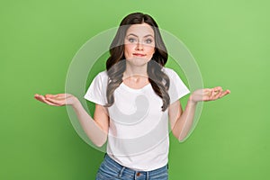 Photo of pretty puzzled woman dressed white t-shirt shrugging shoulders isolated green color background