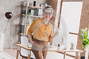 Photo of pretty retired woman cheerful smile hold gadget dressed yellow formalwear modern workplace working home