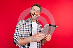 Photo of pretty sweet young gentleman dressed plaid shirt spectacles holding modern gadget isolated red color background