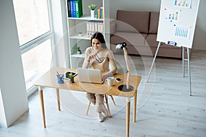 Photo of pretty young businesswoman working at home sitting at the table and typing on laptop