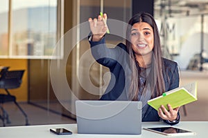 Photo of pretty young girl sit desktop pc hold pen write notepad shirt in home office indoors.