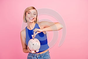 Photo of pretty young woman money bank pig empty space wear blue top isolated on pink color background