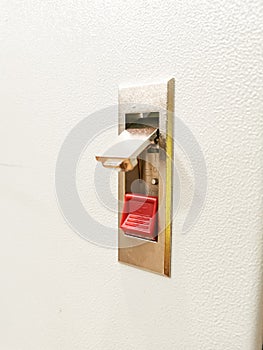 Photo of push lock without key red button mount on electrical cabinet door.