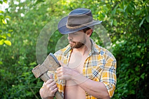 photo of rancher man with axe. rancher with axe. rancher with axe wearing checkered shirt.