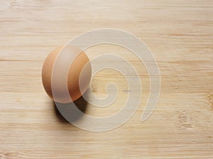 Photo of raw brown chicken egg isolated on wooden background.