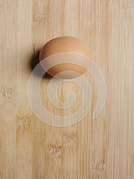 Photo of raw brown chicken egg isolated on wooden background.