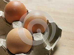Photo of raw brown chicken eggs in egg box.