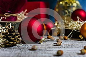 Photo of red balls for decorating a Christmas tree on a wooden table in defocus among cones and hazelnuts