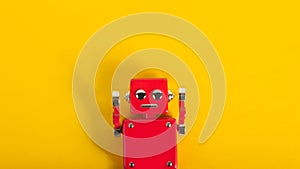 Photo of red colored metal robot toy on orange backdrop