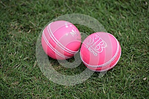 Photo of a red leather cricket ball with stitched seams on grass, cricket ball on green grass pitch with copy space, Close up Cric