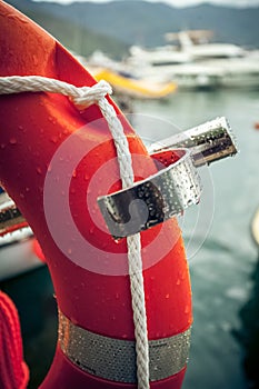 Photo of red lifebuoy with rope against sea port