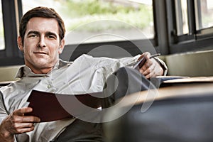 Relaxed successful businessman sitting on sofa while reading