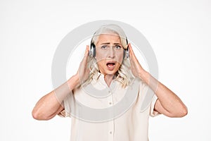 Photo of retired female pensioner with gray hair listening to mu