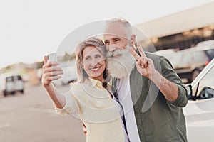 Photo of retired pensioner married people wife husband grey haired old couple selfie v-sign card park outside outdoors