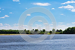 Photo of the river bend on the sunny day against clean blue sky. The steep Bank of the river is covered with dense forest