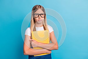 Photo of sad pupil girl do not want do homework wear spectacles hold book  on pastel blue color background