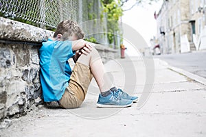 Photo of Sad and Stressed Kid sit by the Wall outdoor