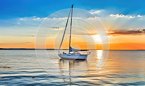 Photo of a sailboat gliding through golden waters at sunset