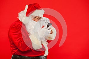 Photo of Santa Claus using mobile phone, on a red background. Ch