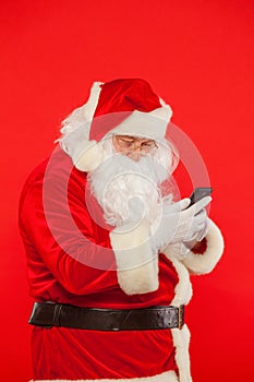 Photo of Santa Claus using mobile phone, on a red background. Ch