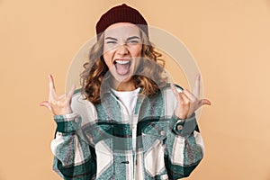 Photo of sassy young woman screaming and making horns with fingers