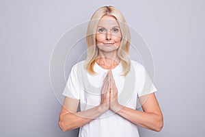 Photo of satisfied aged person hands palms together plead smile look camera isolated on grey color background