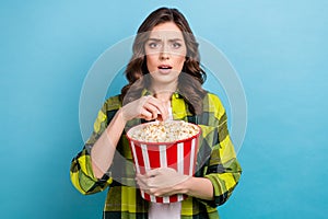 Photo of scared shocked lady wear checkered jacket eating pop corn watching scary movie  blue color background