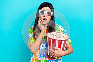 Photo of scared shocked lady wear flower print t-shirt eating pop corn watching horror movie isolated blue color