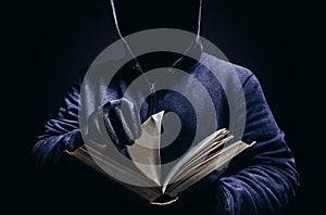 Photo of scary hooded man holding opened book