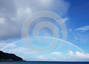 Photo of sea coast with rainbow and cloudy sky