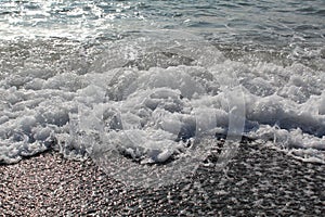 Waves with foam break on the beach shore on the Black Sea