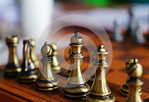 Photo in selective focus of a chess board and metal chess pieces