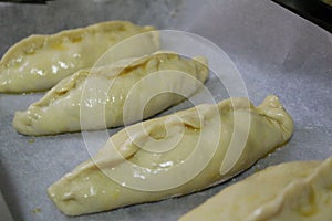Semi-finished products, pies with filling are on baking paper in the oven