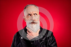 Photo of senior handsome man hand touch beard think ponder minded look empty space isolated over red color background