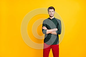 Photo of serious attractive confident man standing with arms crossed wearing red trousers watching his employees pass